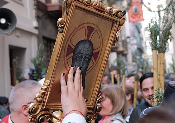 Una mujer toca la imagen de la Santa Faz, a la salida de la Romería desde la concatedral de San Nicolás.