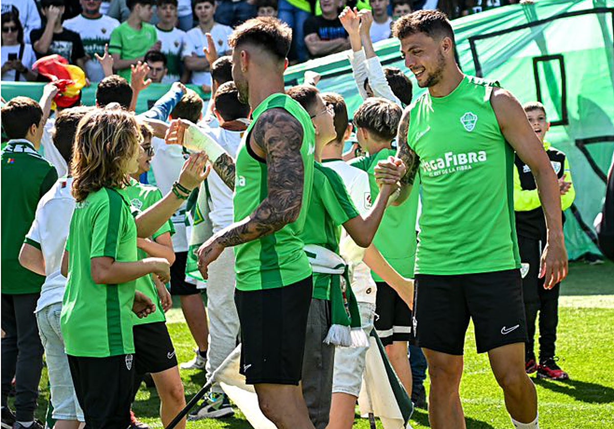Josan y Óscar Plano saludan a varios niños en un entrenamiento.