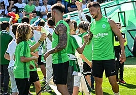 Josan y Óscar Plano saludan a varios niños en un entrenamiento.