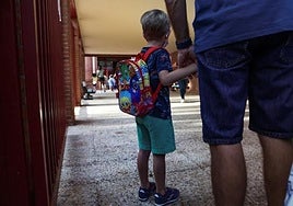 Un niño espera con su padre la entrada al colegio.