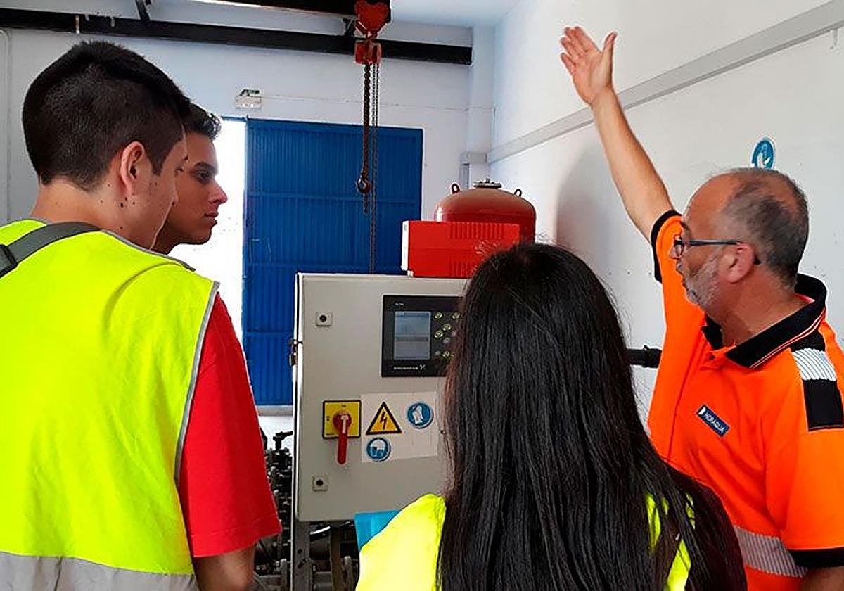 Técnicos de Hidraqua enseñan el funcionamiento de una máquina a unos alumnos.