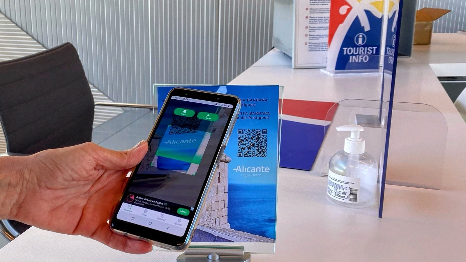 Una personas escanea el qr en la oficina de Turismo.