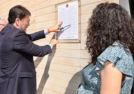El alcalde de Alicante, Luis Barcala, coloca el bando municipal en la puerta del Ayuntamiento, en presencia de la concejal de Fiestas, Cristina Cutanda.