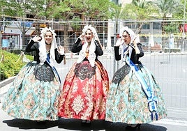 Una bellea y sus damas posan delante de la mascletà en la primera jornada de los disparos de las Hogueras 2024.