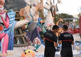 Unos bomberos revisan una hoguera.