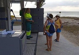 Una empleada explica a unas bañistas la utilidad del punto limpio móvil.