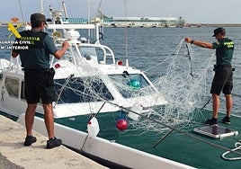 Los agentes, con la red ilegal incautada.