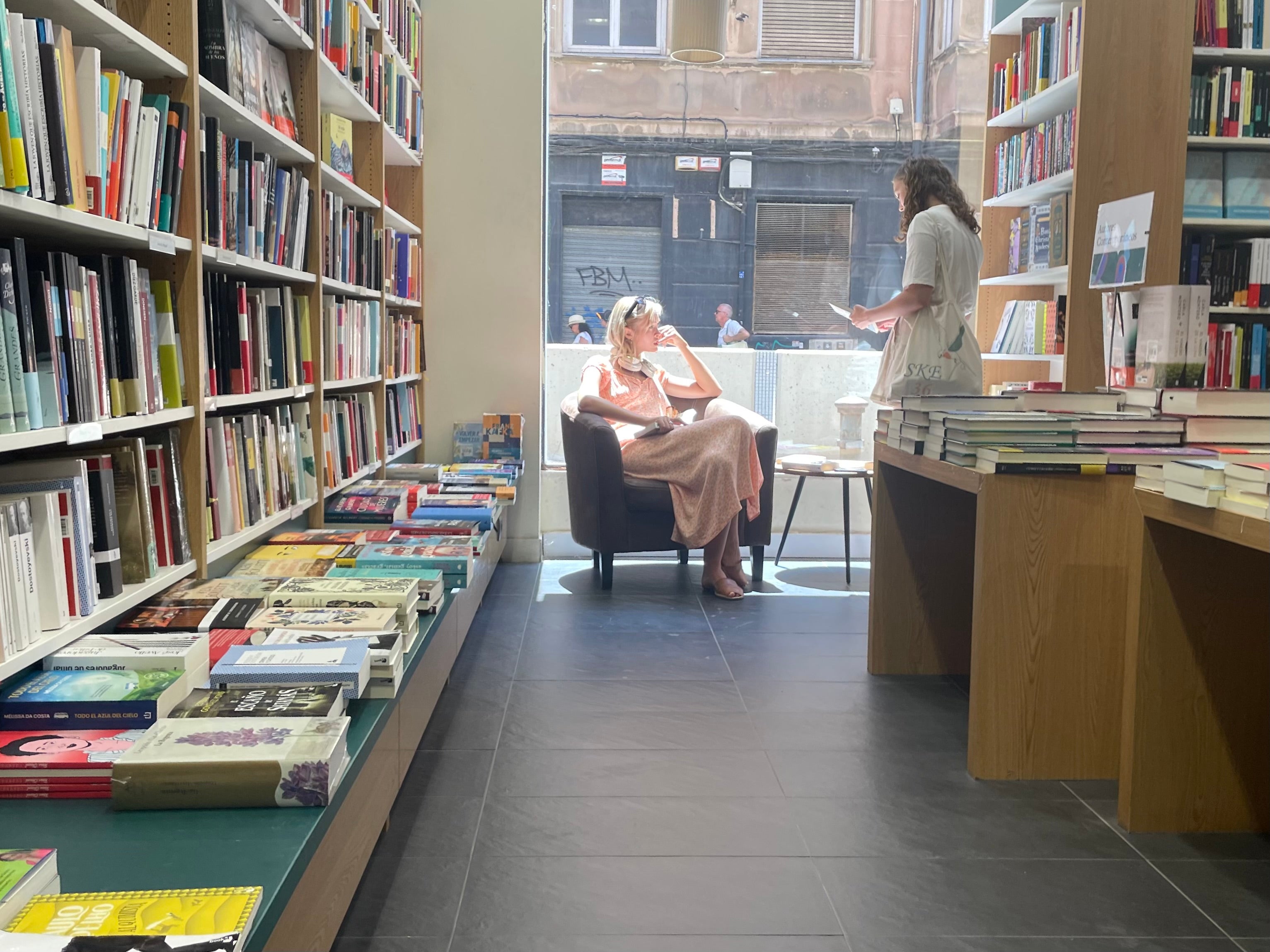 Joven turista leyendo un libro en un sillón de un comercio de Alicante