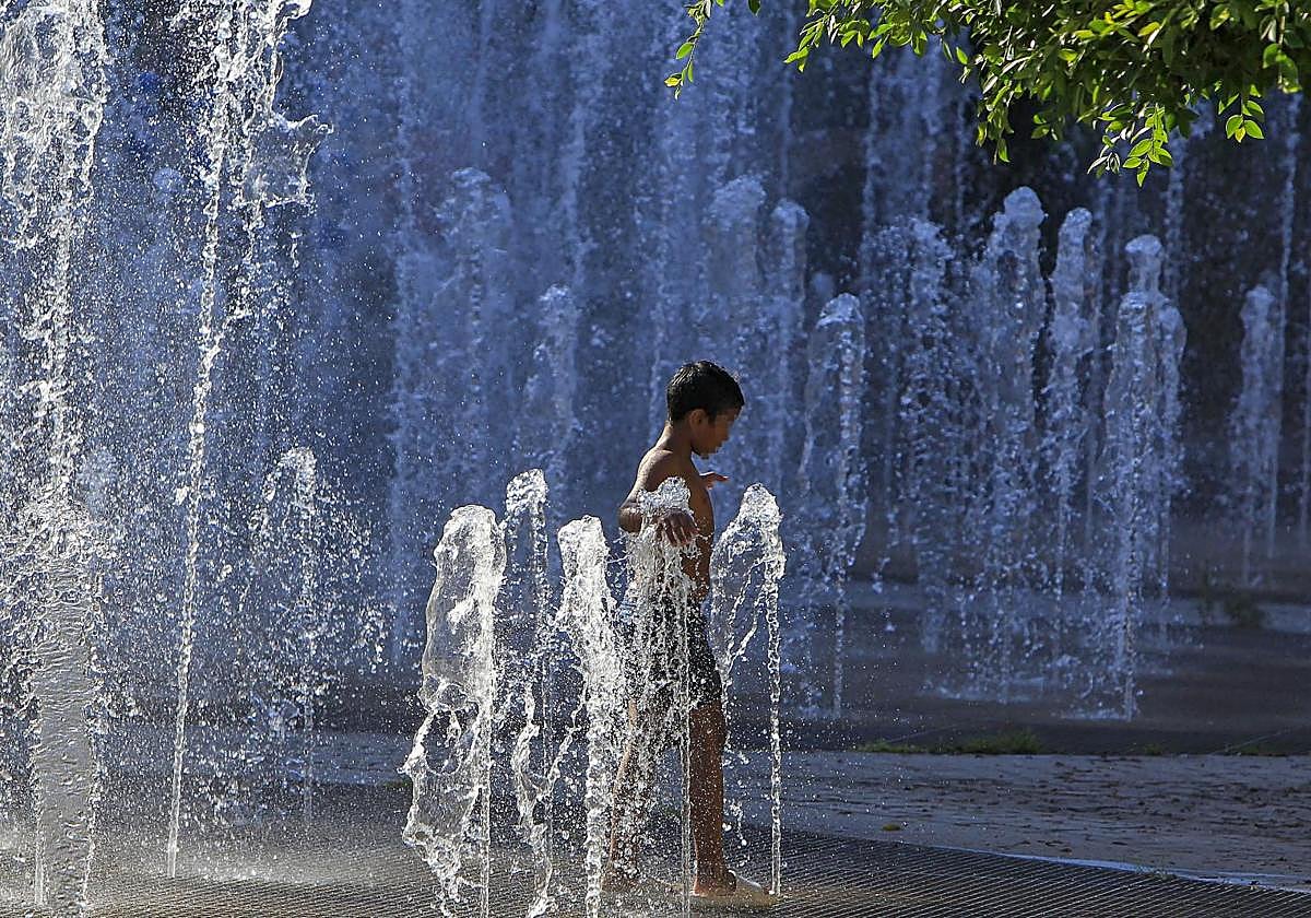 Un niño se refresca en la fuente de la plaza de España, frente a la plaza de toros de Alicante.