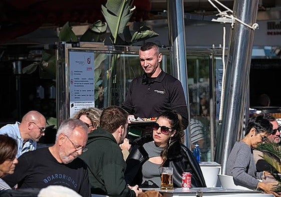 Un camarero atiende unas mesas en una terraza de Alicante.
