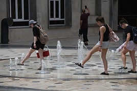 Turistas se refrescan en una fuente de Alicante.
