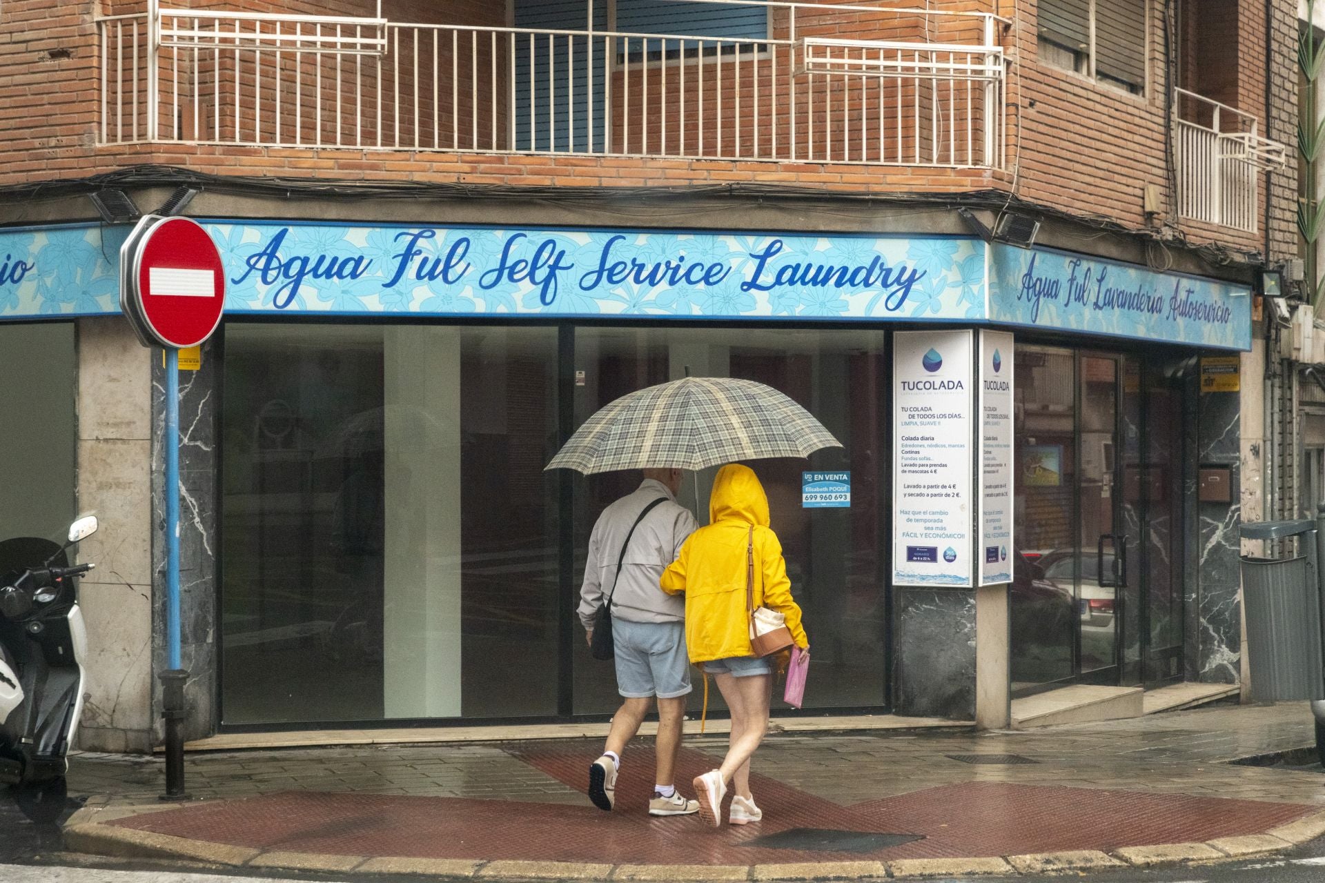 Dos personas se refugian de la lluvia con un paraguas.