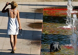 Una mujer se hidrata en la calle ante el intenso calor.