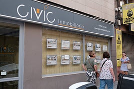 Personas pasan frente a una inmobiliaria de Alicante.