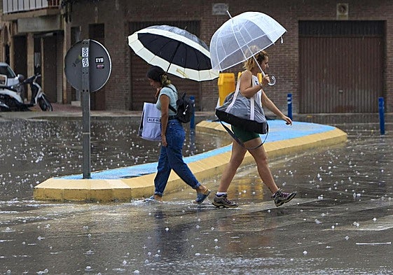 Dos personas cruzan una calle bajo la lluvia este martes en Santa Pola.