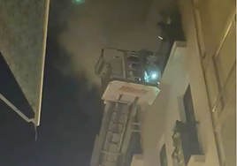 Los bomberos, con el vehículo escalera, acceden al balcón afectado por la humareda.