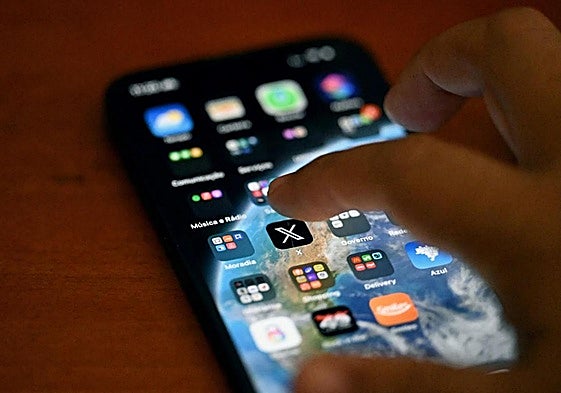 Un joven maneja un teléfono móvil.