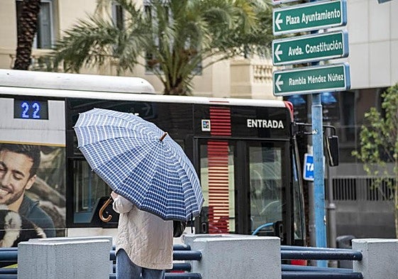 Una mujer se cubre con su paraguas en Alicante.