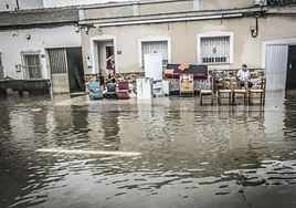 Un señor, sentado, contemplando las inundadas calles de Orihuela.