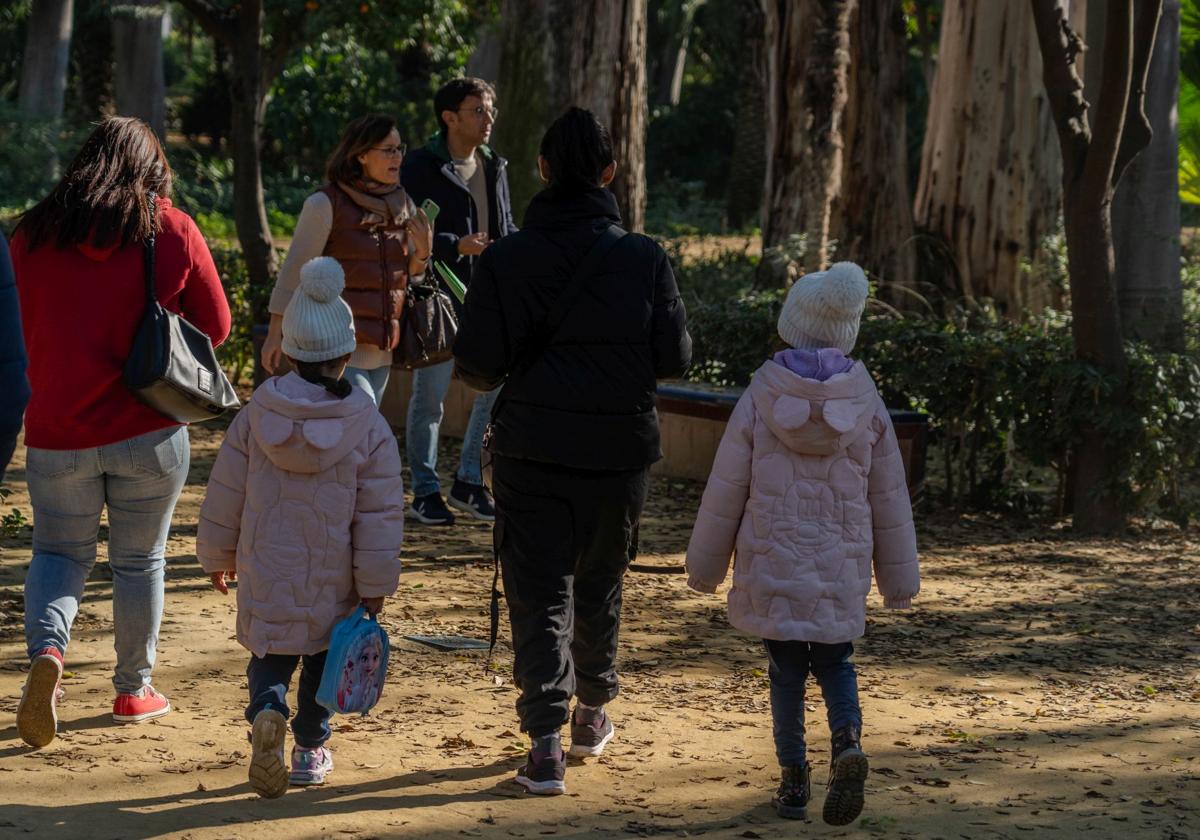 Varias personas pasean por un parque con abrigos.