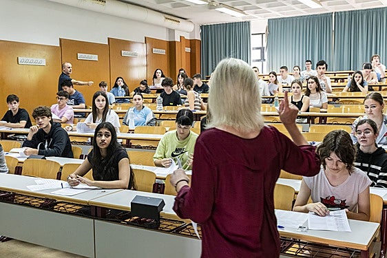 Una docente reparte exámenes en una aula de Alicante.