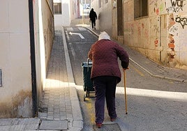 Una persona mayor camina por la calzada en una calle del barrio alicantino.