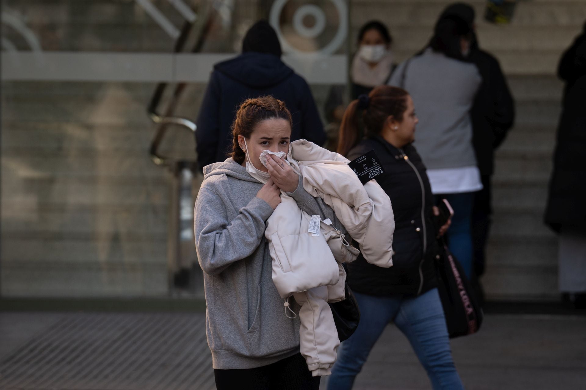 Una joven portando una mascarilla a la entrada de un centro sanitario.