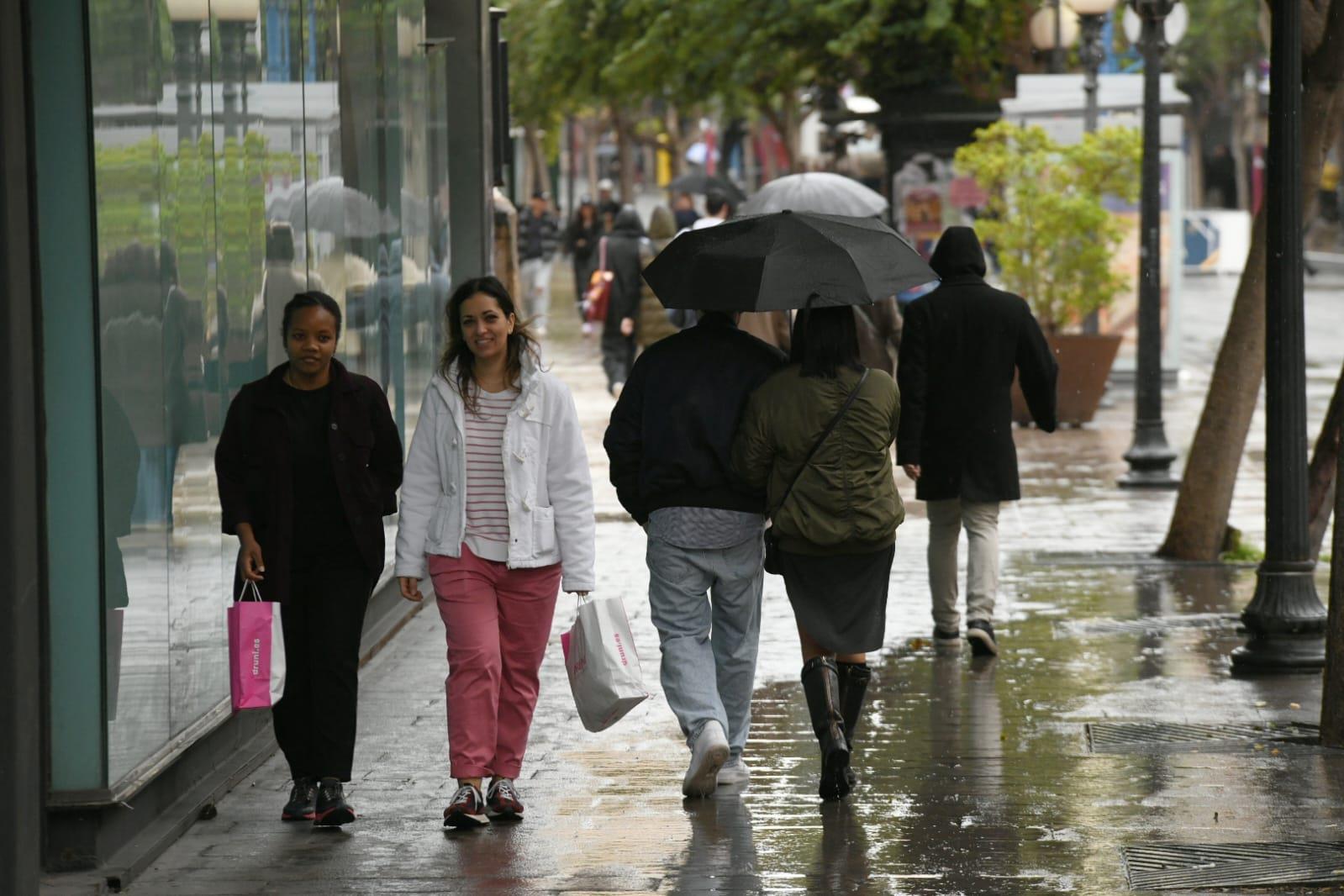 Personas pasean por la Rambla mientras se montan los escenarios del carnaval bajo la lluvia,