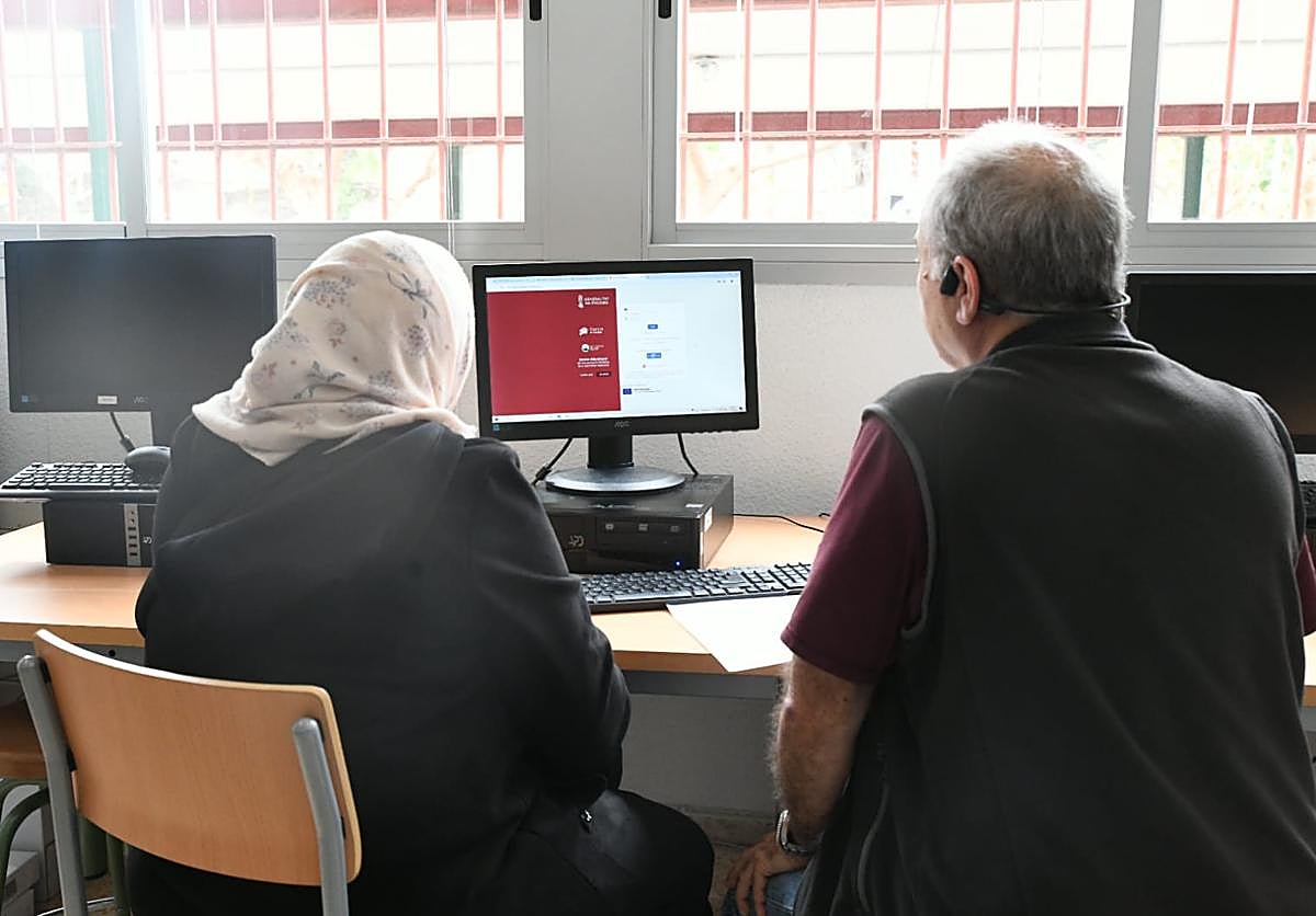 A mother is assisted by a worker at an Alicante institute to participate in the consultation.