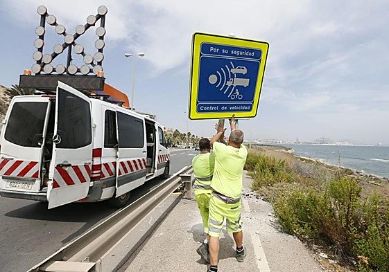 Operarios municipales colocan una señal de tráfico.