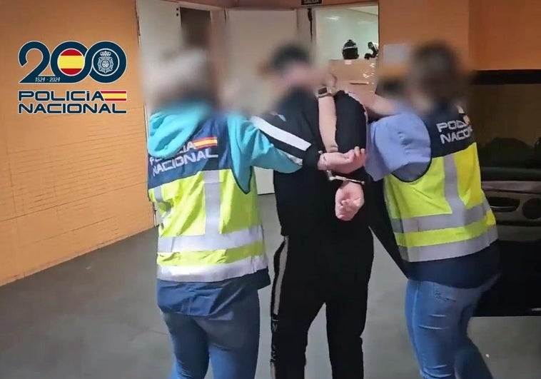 Dos agentes trasladan al detenido en dependencias policiales.