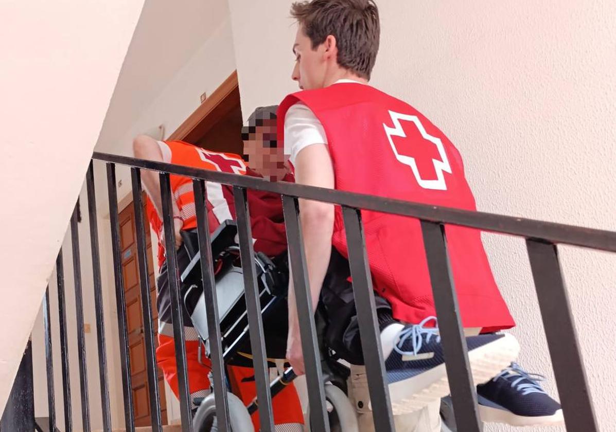 A Red Cross volunteer assists an elderly woman to her home.