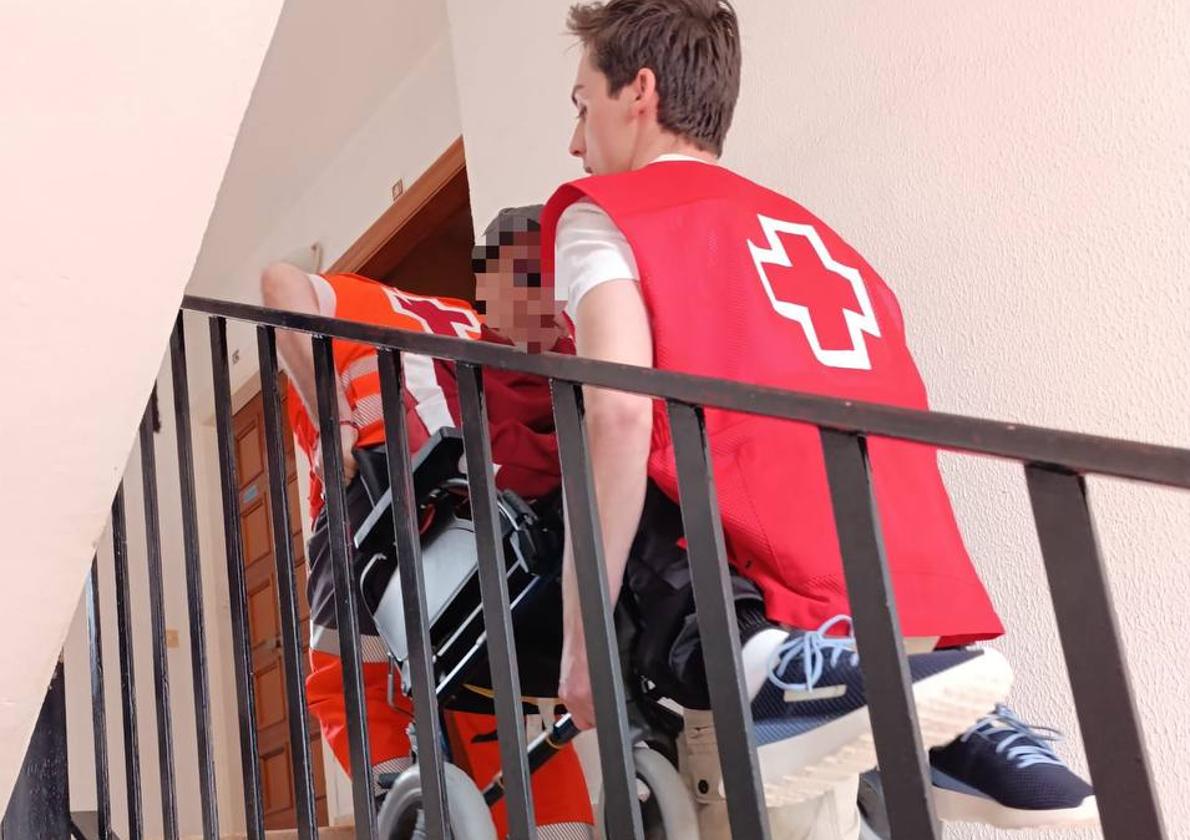 Voluntario de Cruz Roja traslada a una señora mayor a su domicilio.