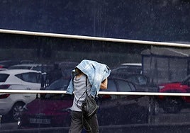 Una mujer se dirige a comprar en medio de una intensa lluvia.