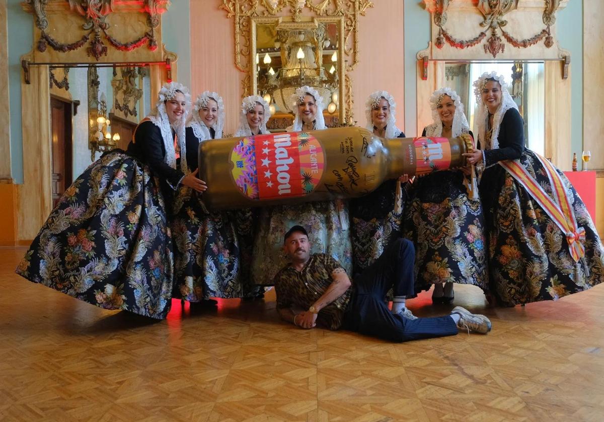 La bellea del foc y sus dames d'honor sostienen un botellín gigante diseñado por Antonyo Marest.