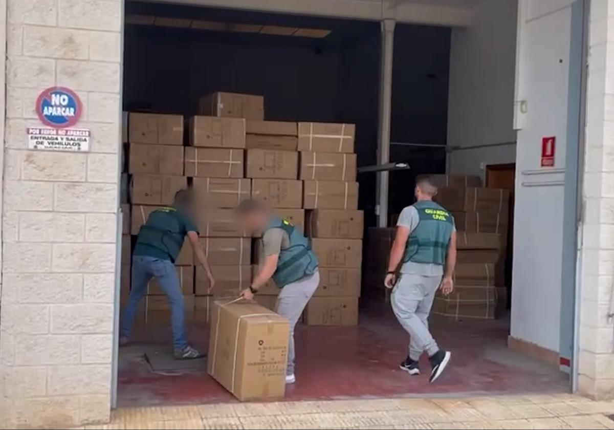 Agentes de la Guardia Civil requisan cajas con parte de la mercancía ilegal.