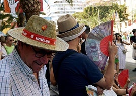 Varias personas se protegen del calor en la mascletà de las Hoguera.