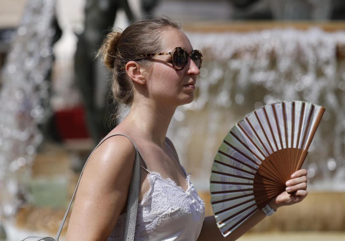A pedestrian fans herself to combat the heat.