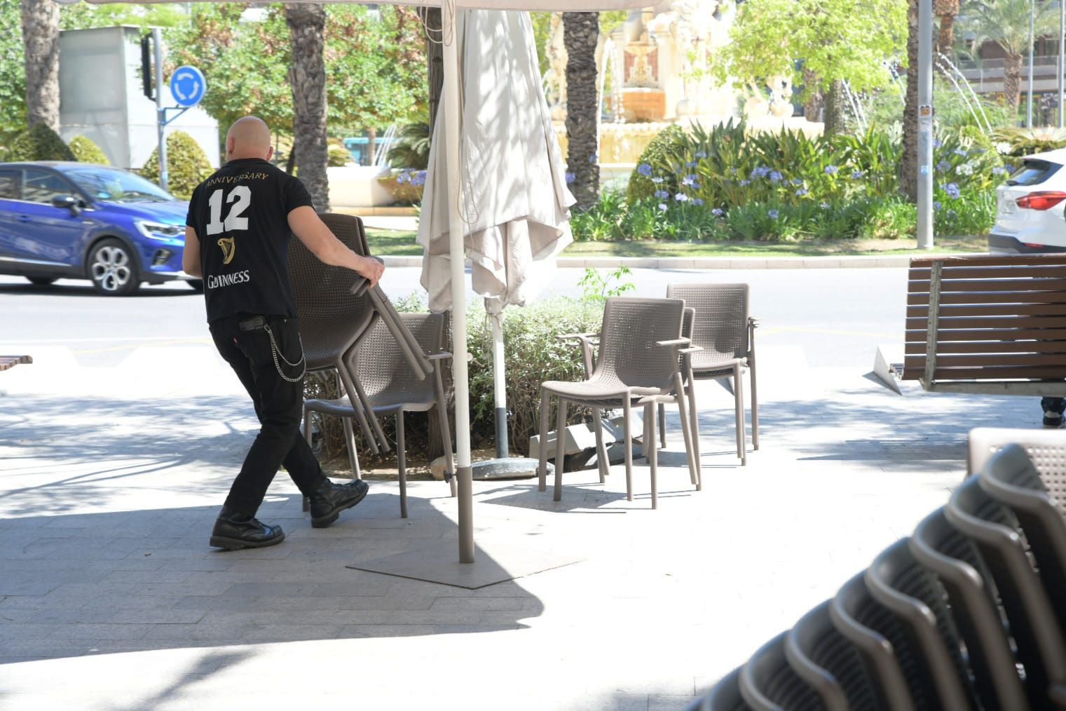 A waiter sets up chairs on a terrace in Alicante.