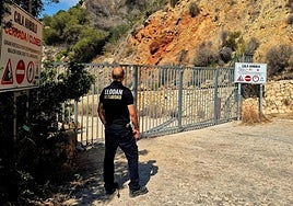Un empleado de seguridad custodia la entrada de la cala Ambolo de Xàbia, desalojada este lunes por riesgo de desprendimiento.