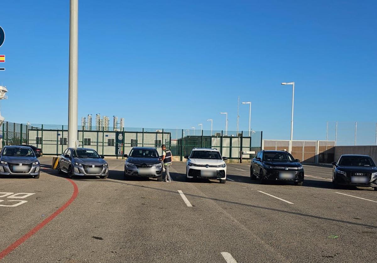 Un agente de la Policía Nacional junto a los vehículos robados decomisados en el Puerto de Alicante.