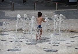 Un niño se refresca jugando en una fuente de Alicante.