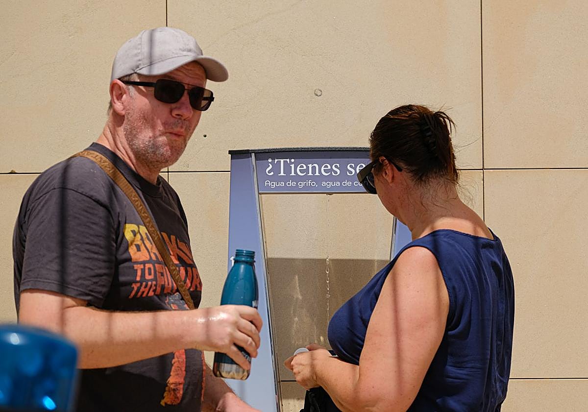 Imagen principal - Varias personas utilizan las fuentes de agua en Alicante. 
