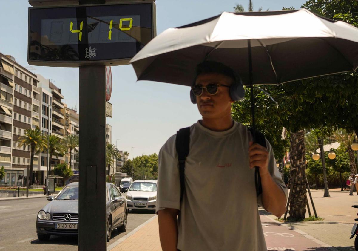A man walks beside a thermometer.