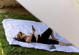 Una persona tumbada en un parque para huir del calor.