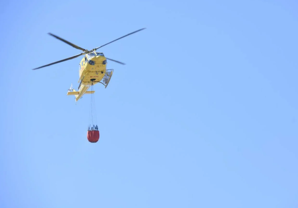 Helicóptero del Consorcio Provincial después de cargar agua en un depósito.