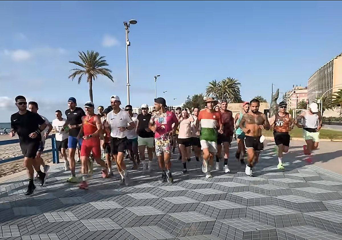 Los participantes en el reto, con Pitufollow a la cabeza, recorren el paseo de la Playa del Postiguet.