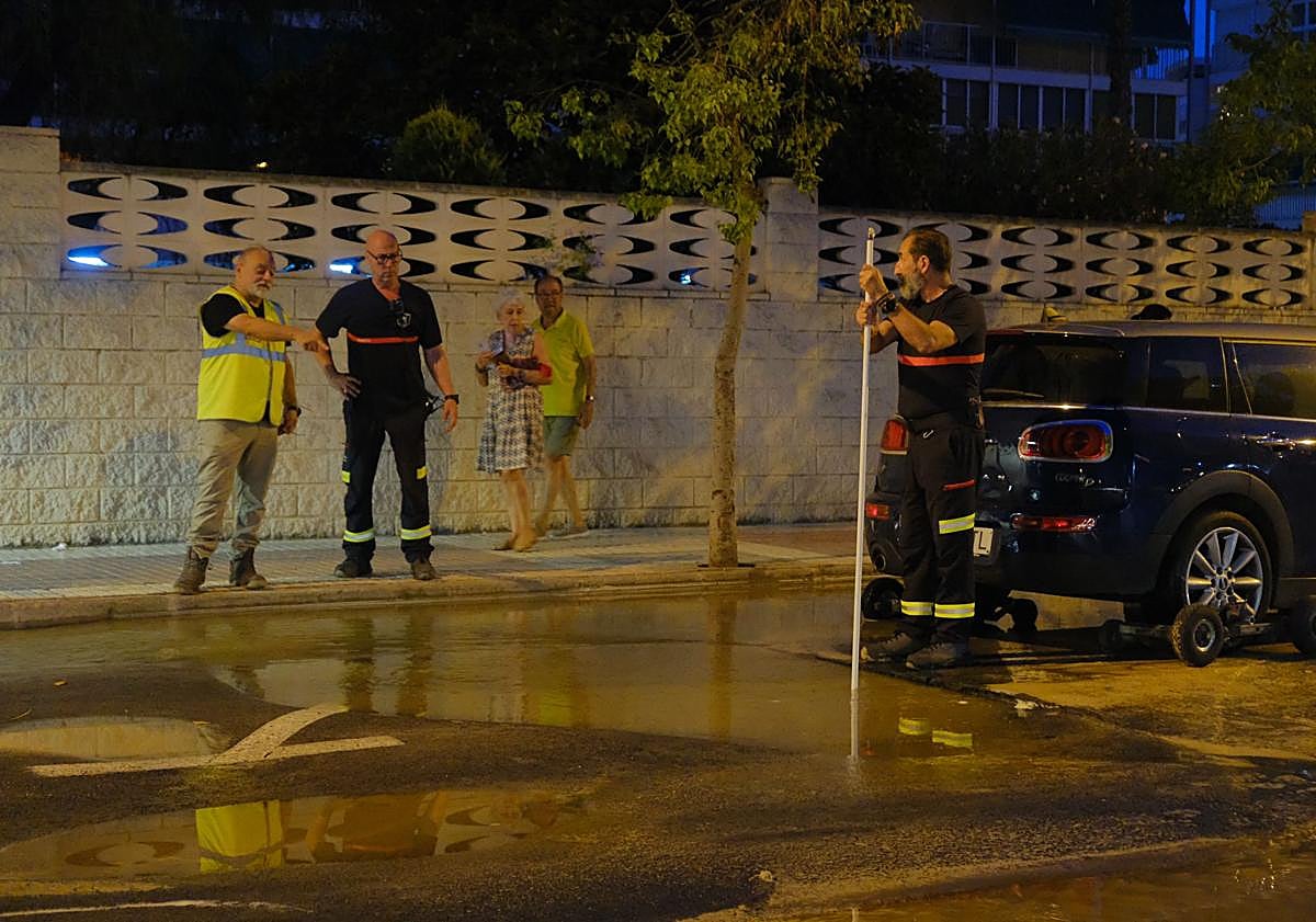 Imagen principal - 1. Un bombero comprueba la profundidad del socavón. 2. Tratan de sacar el vehículo atascado. 3. Restos en la calle de las aguas fecales.
