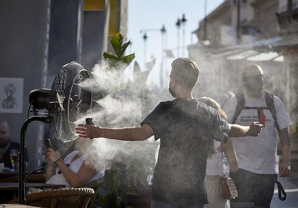 Um hombre busca la forma de refrescarse en plena calle.