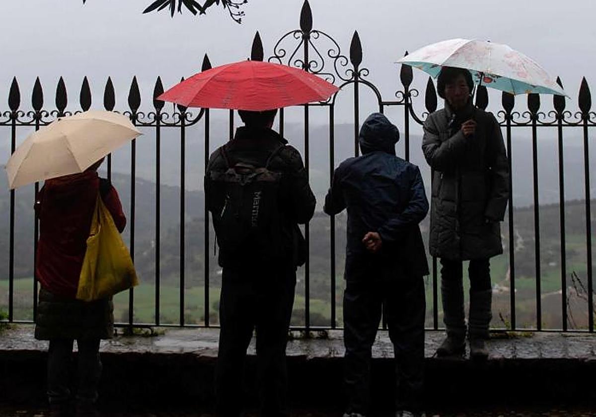 Unas personas bajo la lluvia, con sus paraguas.